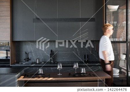 Individual strolling within stylish modern kitchen environment Individual strolling within stylish modern kitchen environment 142264476