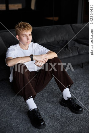 Young man relaxes thoughtfully on sofa as sunlight filters through window Young man relaxes thoughtfully on sofa as sunlight filters through window 142264483