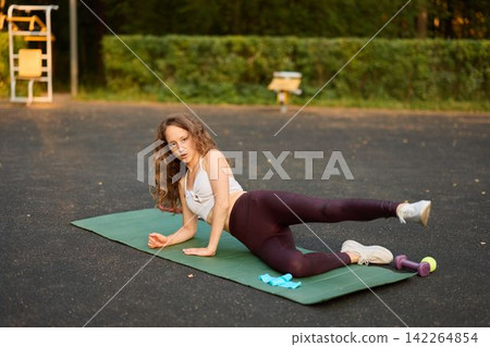Trainer demonstrating sideline glute activation exercise outdoors Trainer demonstrating sideline glute activation exercise outdoors 142264854