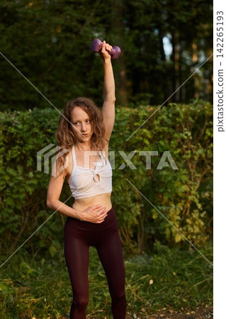 Caucasian woman portrait performing powerful overhead dumbbell lift Caucasian woman portrait performing powerful overhead dumbbell lift 142265193