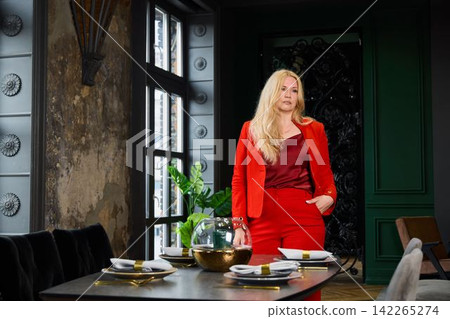 Elegant white figure showcasing fashionable ensemble beside table setting Elegant white figure showcasing fashionable ensemble beside table setting 142265274