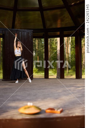 Lone dancer maintains poised arabesque against scenic background Lone dancer maintains poised arabesque against scenic background 142265345