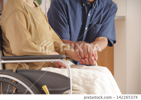A middle-aged husband comforts his wife in a wheelchair. A middle-aged husband comforts his wife in a wheelchair. 142265374