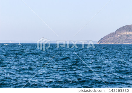 A seascape with the open ocean, distant islands, and sailboats. Blue sea and waves. A seascape with the open ocean, distant islands, and sailboats. Blue sea and waves. 142265880