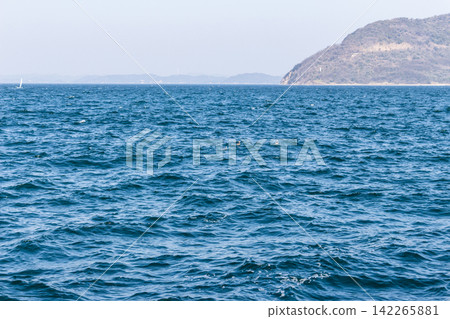 A seascape with the open ocean, distant islands, and a small boat in view. Blue sea and waves. A seascape with the open ocean, distant islands, and a small boat in view. Blue sea and waves. 142265881