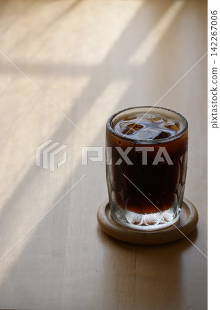 Iced coffee placed by a window where sunlight streams in. 142267006