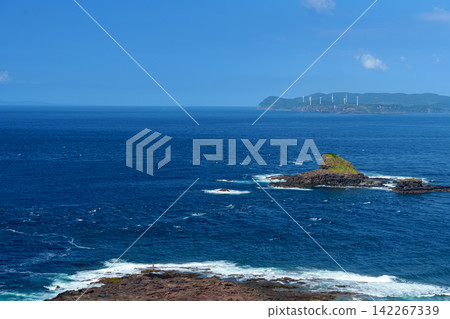 The clear blue sea and the rocky shore where white waves crash. 142267339