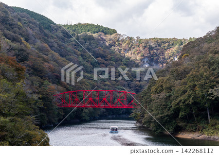 Autumn valleys and red bridges, sightseeing boats gliding across the lake, mountains covered in autumn foliage and natural scenery. Autumn valleys and red bridges, sightseeing boats gliding across the lake, mountains covered in autumn foliage and natural scenery. 142268112