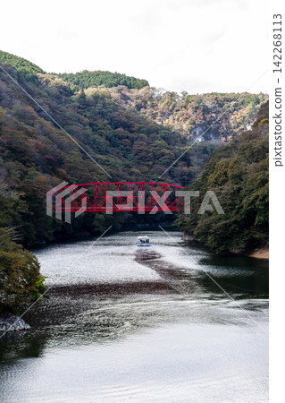 Autumn valleys and red bridges, sightseeing boats navigating the lake, mountains covered in autumn foliage and natural scenery. Autumn valleys and red bridges, sightseeing boats navigating the lake, mountains covered in autumn foliage and natural scenery. 142268113