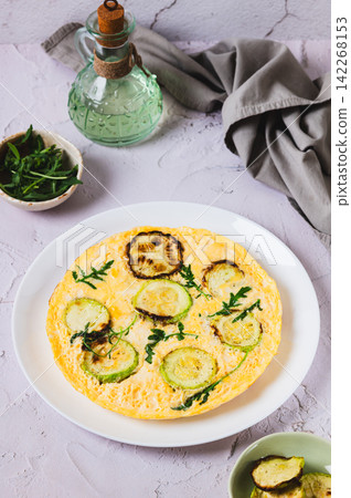 Delicious zucchini omelette with cheese and herbs on a plate on the table vertical view Delicious zucchini omelette with cheese and herbs on a plate on the table vertical view 142268153