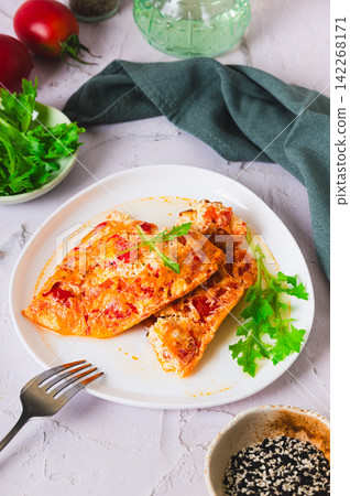 Tomato cheese omelette with herbs on a plate on the table vertical view Tomato cheese omelette with herbs on a plate on the table vertical view 142268171