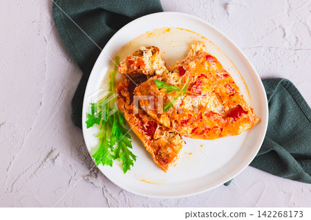 Close up of airy egg omelette with tomatoes on a plate on the table top view Close up of airy egg omelette with tomatoes on a plate on the table top view 142268173