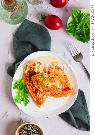 Tomato cheese omelette with herbs on a plate on the table top and vertical view 142268174