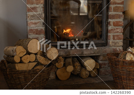 Brick fireplace with burning wood and logs in wicker baskets Brick fireplace with burning wood and logs in wicker baskets 142268390