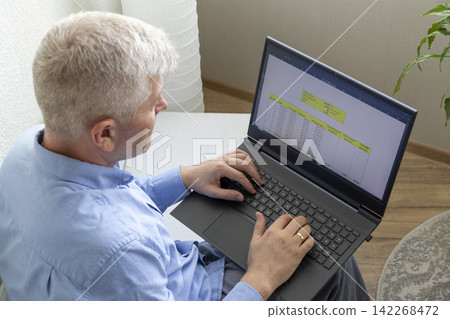 Senior Businessman Reviewing Mortgage Amortization Table on Laptop While Relaxing at Home Senior Businessman Reviewing Mortgage Amortization Table on Laptop While Relaxing at Home 142268472