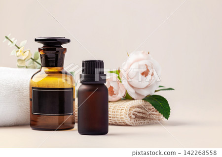 Spa and wellness background, essential oil bottles, towels with white roses and green leaves decoration Spa and wellness background, essential oil bottles, towels with white roses and green leaves decoration 142268558