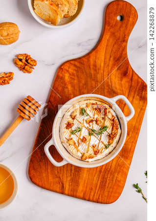 Baked cheese with honey and walnuts on a wooden board Baked cheese with honey and walnuts on a wooden board 142268879