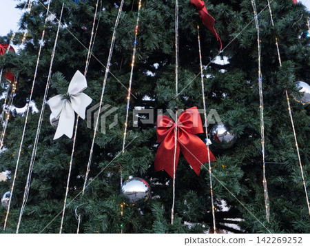 Decorated Christmas tree with red and white bows and silver baubles. Festive holiday background with vertical string lights. Winter celebration texture Decorated Christmas tree with red and white bows and silver baubles. Festive holiday background with vertical string lights. Winter celebration texture 142269252