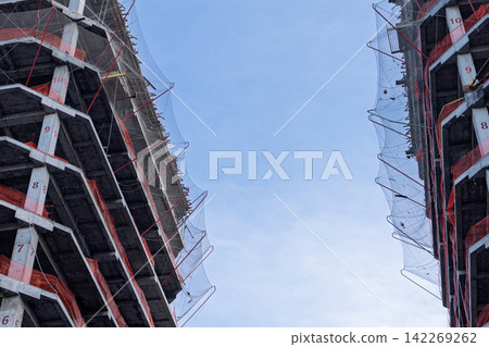 Concrete high-rise buildings under construction with protective safety nets 142269262