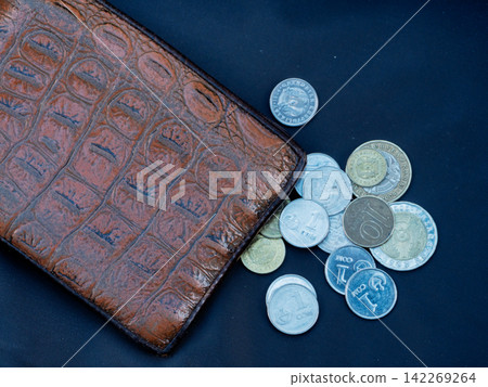 Brown leather wallet with scattered Kazakhstani Tenge coins on dark blue background. Finance and economy concept flat lay. Copy space Brown leather wallet with scattered Kazakhstani Tenge coins on dark blue background. Finance and economy concept flat lay. Copy space 142269264