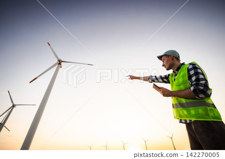 Wind Energy Worker Pointing Toward Turbines at Sunset Wind Energy Worker Pointing Toward Turbines at Sunset 142270005