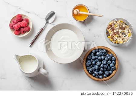 Healthy yogurt breakfast with berries, muesli and honey on marble background Healthy yogurt breakfast with berries, muesli and honey on marble background 142270036