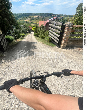 Cycling through a rural village with scenic countryside views Cycling through a rural village with scenic countryside views 142270069