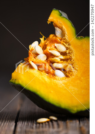 Close up of fresh pumpkin slice with seeds in shallow depth of field Close up of fresh pumpkin slice with seeds in shallow depth of field 142270947