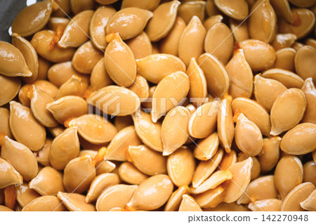 Close up of raw pumpkin seeds filling frame with natural texture Close up of raw pumpkin seeds filling frame with natural texture 142270948