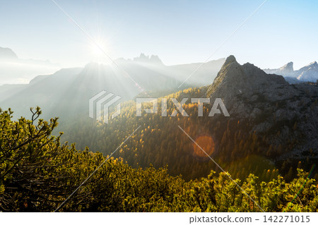 Sunbeams break through mountain haze above autumn forests Sunbeams break through mountain haze above autumn forests 142271015