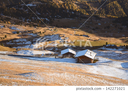 Traditional mountain huts on snow-covered alpine meadows 142271021