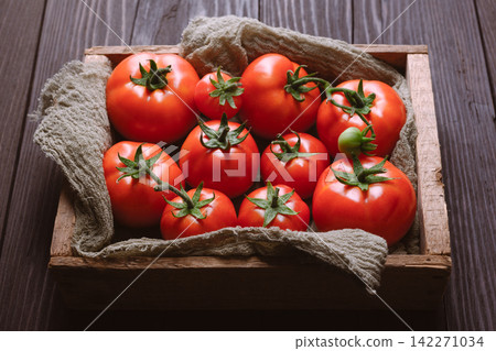 Wooden crate filled with fresh tomatoes on rustic table Wooden crate filled with fresh tomatoes on rustic table 142271034