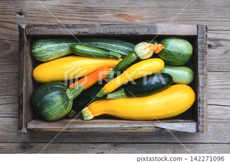 Wooden crate with mixed zucchini on wooden background Wooden crate with mixed zucchini on wooden background 142271096
