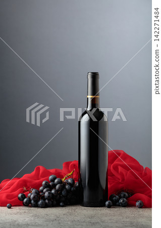 Bottle of red wine with grapes on a grey background. Bottle of red wine with grapes on a grey background. 142271484