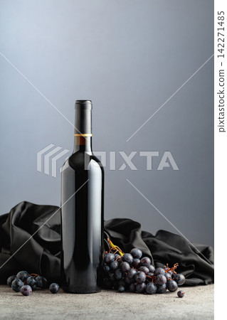 Bottle of red wine with grapes on a grey background. Bottle of red wine with grapes on a grey background. 142271485