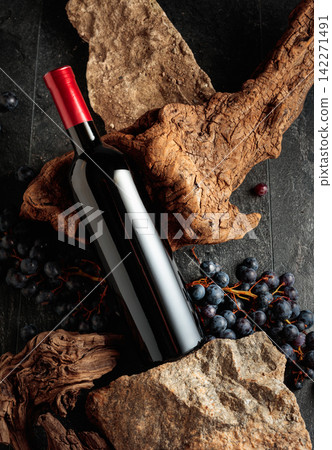 Bottle of red wine with stones, dried snags, and blue grapes. Bottle of red wine with stones, dried snags, and blue grapes. 142271491