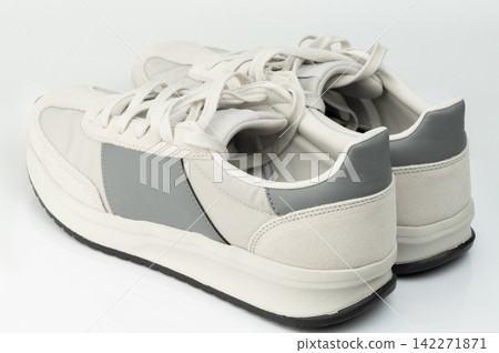 New sneakers in light colors with gray accents on a white surface New sneakers in light colors with gray accents on a white surface 142271871