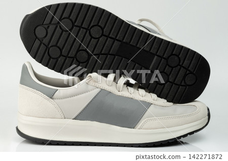 Running shoes with gray and white design on display Running shoes with gray and white design on display 142271872