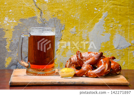 beer pretzel and mustard on a wooden table. rustic oktoberfest drink and food background. grungy wall texture beer pretzel and mustard on a wooden table. rustic oktoberfest drink and food background. grungy wall texture 142271897