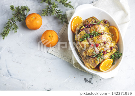 Roasted pork in white dish, christmas baked ham with cranberries, tangerines, thyme, rosemary, garlic on light table surface Roasted pork in white dish, christmas baked ham with cranberries, tangerines, thyme, rosemary, garlic on light table surface 142271959