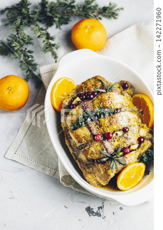 Roasted pork in white dish, christmas baked ham with cranberries, tangerines, thyme, rosemary, garlic on light table surface Roasted pork in white dish, christmas baked ham with cranberries, tangerines, thyme, rosemary, garlic on light table surface 142271960
