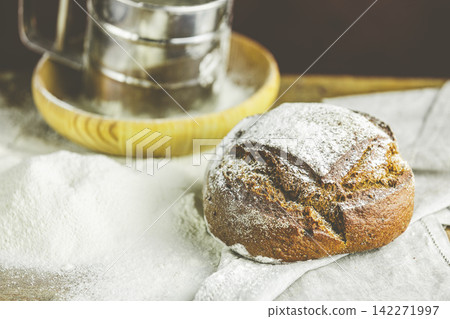 Fresh bread on table close-up in flour placer. Fresh bread on the kitchen table. The healthy eating and traditional bakery concept. Rustic style Fresh bread on table close-up in flour placer. Fresh bread on the kitchen table. The healthy eating and traditional bakery concept. Rustic style 142271997