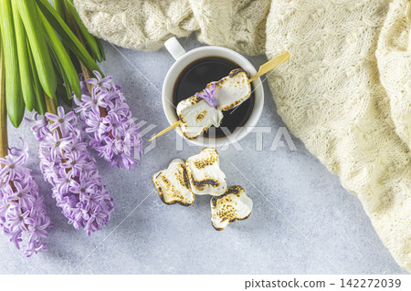 Cup of coffee with milk and delicious fried marshmallow and pink hyacinths on light concrete surface background. Top view, copy space Cup of coffee with milk and delicious fried marshmallow and pink hyacinths on light concrete surface background. Top view, copy space 142272039
