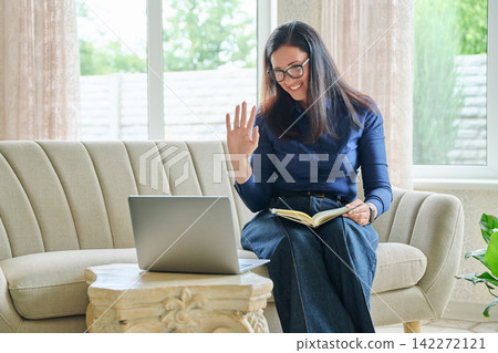 Smiling woman having video call on laptop at home Smiling woman having video call on laptop at home 142272121
