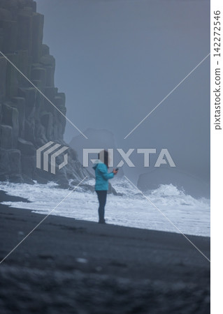 Woman Running on Black Sand Beach with Basalt Cliffs in Iceland Woman Running on Black Sand Beach with Basalt Cliffs in Iceland 142272546