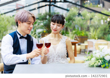 The bride and groom drinking wine on a waterside terrace. The bride and groom drinking wine on a waterside terrace. 142272901