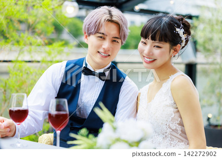 The bride and groom drinking wine on a waterside terrace. The bride and groom drinking wine on a waterside terrace. 142272902