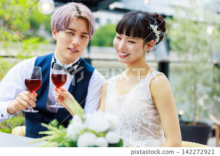 The bride and groom drinking wine on a waterside terrace. The bride and groom drinking wine on a waterside terrace. 142272921