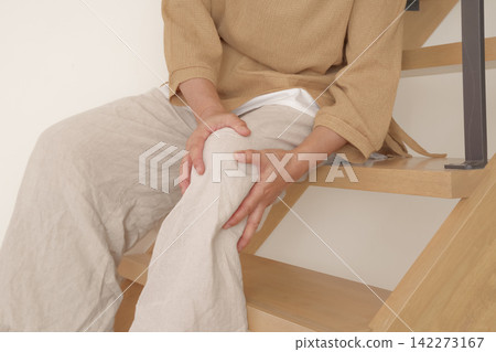 一名女子上下樓梯時膝蓋疼痛。 一名女子上下樓梯時膝蓋疼痛。 142273167