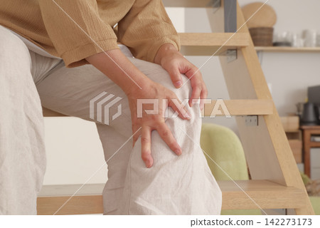 一名女子上下樓梯時膝蓋疼痛。 一名女子上下樓梯時膝蓋疼痛。 142273173